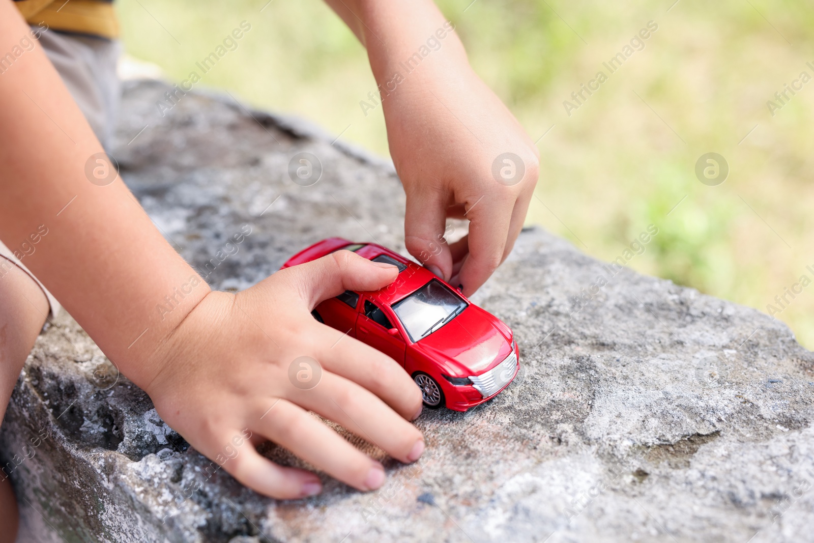 Little boy playing with toy car outdoors, closeup Photo of Little boy playing with toy car outdoors, closeup