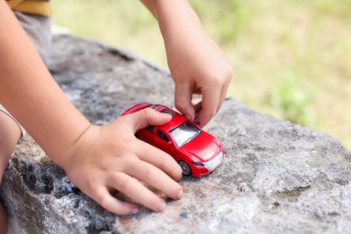 Photo of Little boy playing with toy car outdoors, closeup