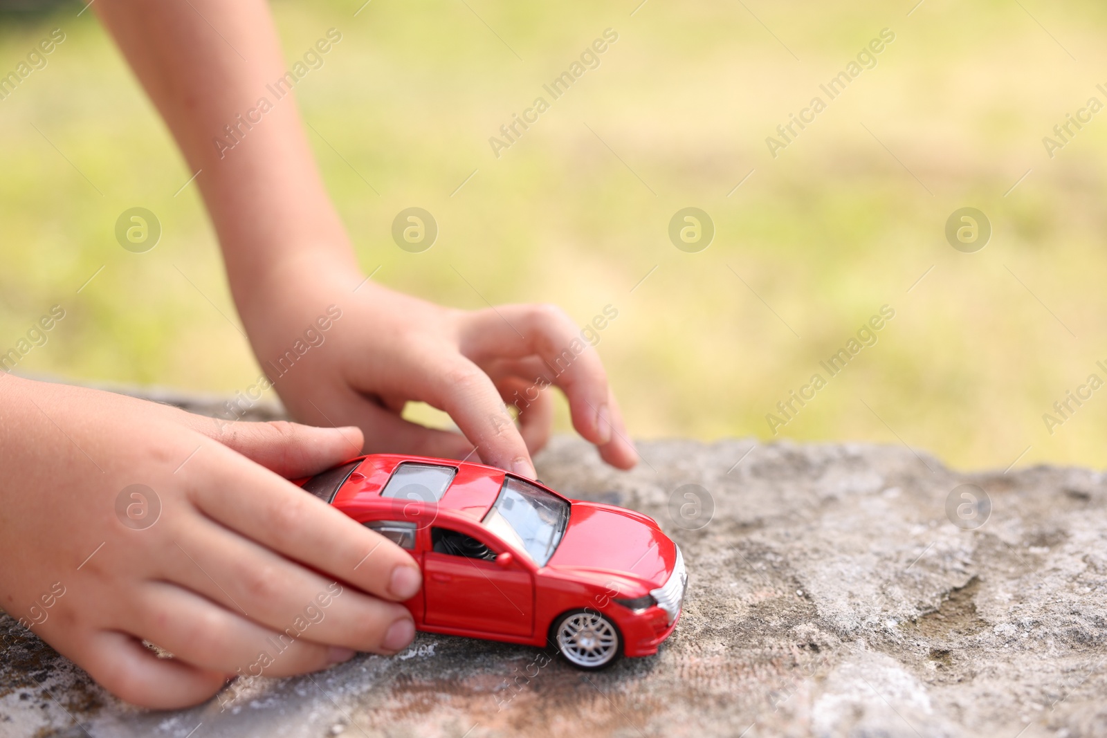 Little boy playing with toy car outdoors, closeup. Space for text Photo of Little boy playing with toy car outdoors, closeup. Space for text