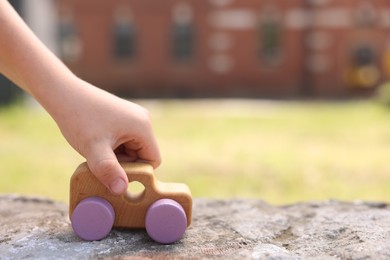 Photo of Little boy playing with toy car outdoors, closeup. Space for text