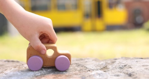 Photo of Little boy playing with toy car outdoors, closeup. Space for text