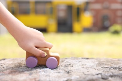 Photo of Little boy playing with toy car outdoors, closeup. Space for text
