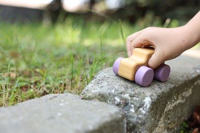 Photo of Little boy playing with toy car outdoors, closeup. Space for text