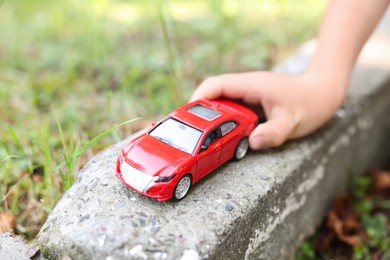 Photo of Little boy playing with toy car outdoors, closeup