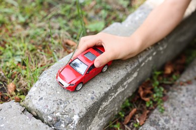Photo of Little boy playing with toy car outdoors, closeup