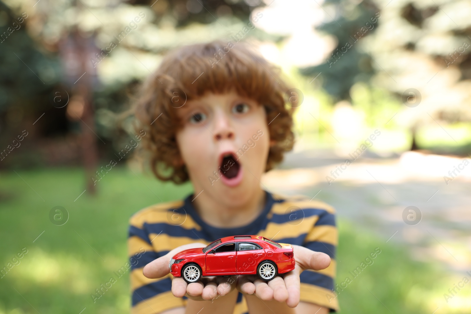 Surprised little boy with toy car outdoors, selective focus Photo of Surprised little boy with toy car outdoors, selective focus