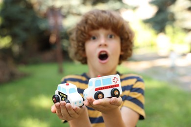 Photo of Little boy with toy cars outdoors, selective focus