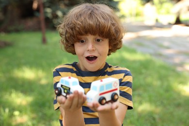 Photo of Surprised little boy with toy cars outdoors