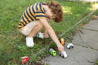 Photo of Little boy playing with toy cars outdoors