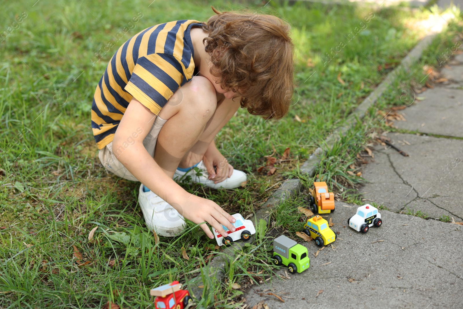 Little boy playing with toy cars outdoors Photo of Little boy playing with toy cars outdoors