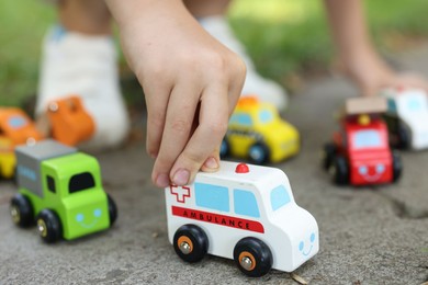 Photo of Little boy playing with toy cars outdoors, closeup