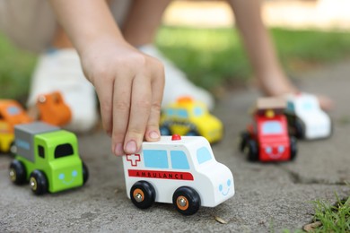 Photo of Little boy playing with toy cars outdoors, closeup