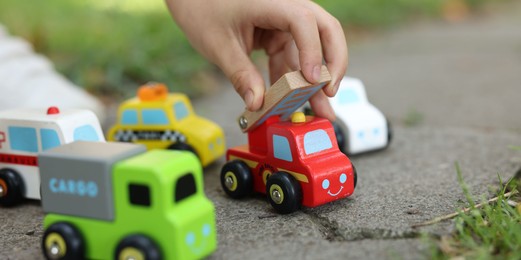 Photo of Little boy playing with toy cars outdoors, closeup