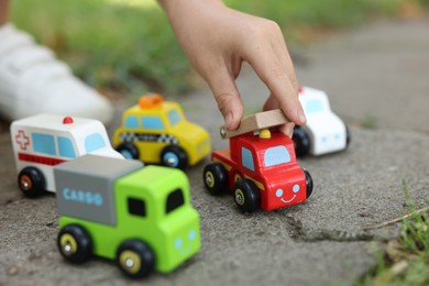 Photo of Little boy playing with toy cars outdoors, closeup