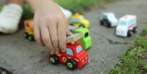 Photo of Little boy playing with toy cars outdoors, closeup