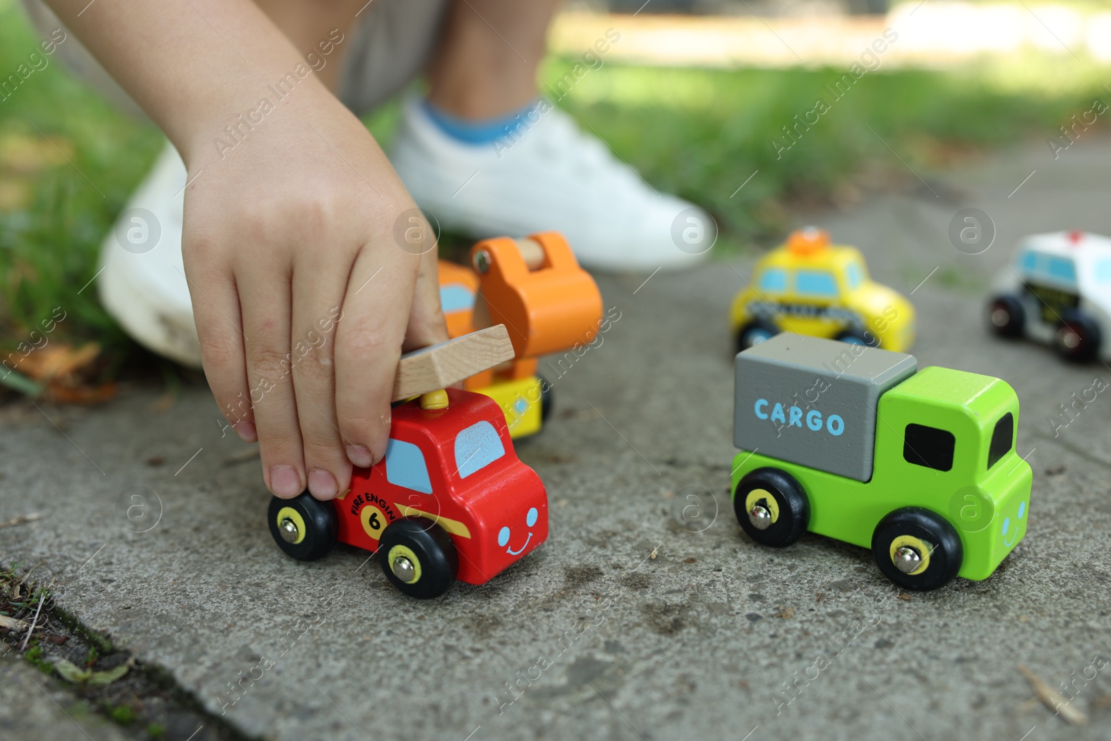 Little boy playing with toy cars outdoors, closeup Photo of Little boy playing with toy cars outdoors, closeup