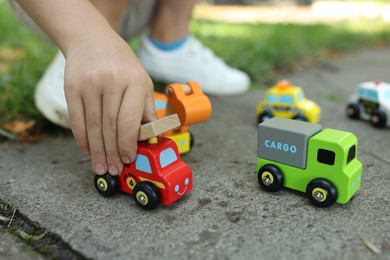 Photo of Little boy playing with toy cars outdoors, closeup