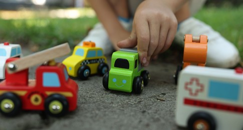 Photo of Little boy playing with toy cars outdoors, closeup