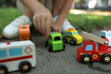 Photo of Little boy playing with toy cars outdoors, closeup