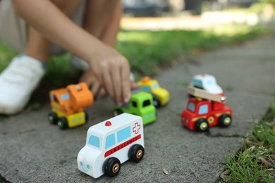 Photo of Little boy playing with toy cars outdoors, closeup