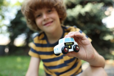 Photo of Little boy with toy car outdoors, selective focus