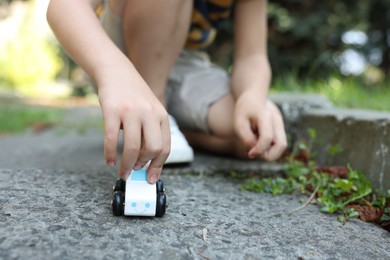 Photo of Little boy playing with toy car outdoors, closeup