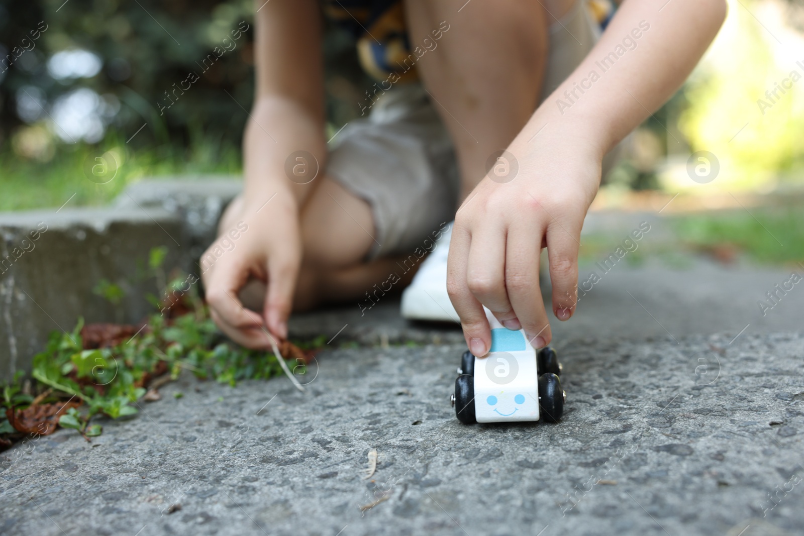 Little boy playing with toy car outdoors, closeup Photo of Little boy playing with toy car outdoors, closeup