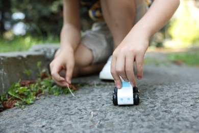 Photo of Little boy playing with toy car outdoors, closeup