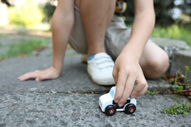 Photo of Little boy playing with toy car outdoors, closeup