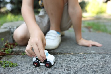 Photo of Little boy playing with toy car outdoors, closeup