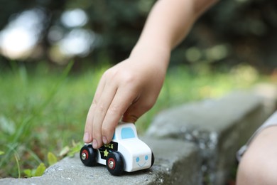 Photo of Little boy playing with toy car outdoors, closeup