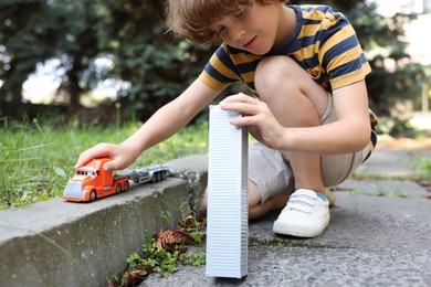 Photo of Little boy playing with toy car outdoors