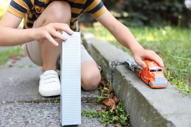 Photo of Little boy playing with toy car outdoors, closeup
