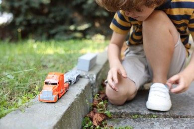Photo of Little boy playing with toy car outdoors, closeup