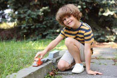 Photo of Little boy playing with toy car outdoors