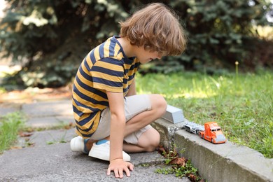 Photo of Little boy playing with toy car outdoors