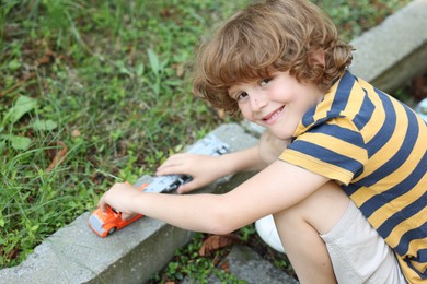 Photo of Little boy playing with toy car outdoors