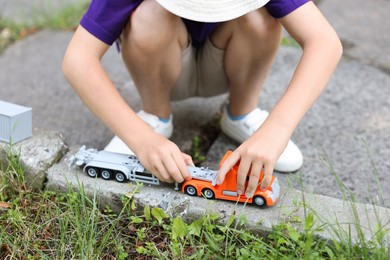 Photo of Little boy playing with toy car outdoors, closeup