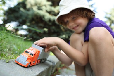 Photo of Little boy playing with toy car outdoors, selective focus