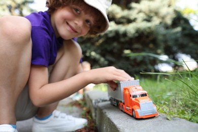 Photo of Little boy playing with toy car outdoors, selective focus
