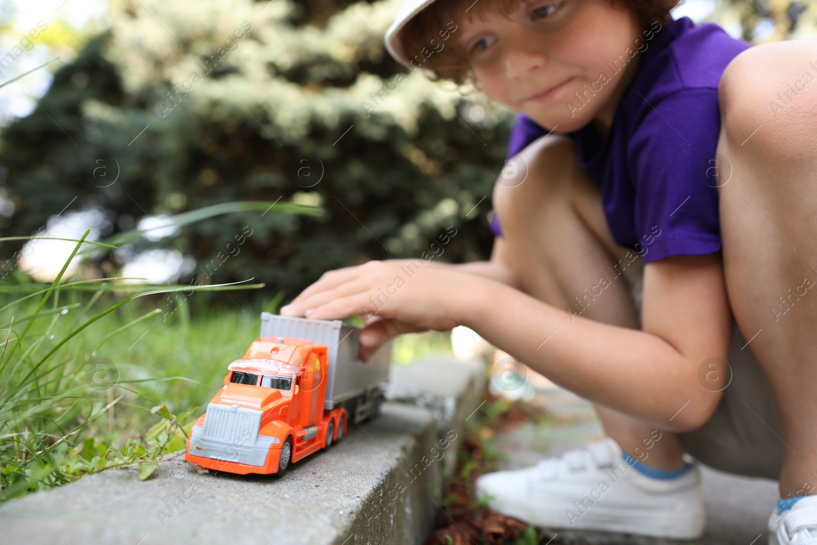 Little boy playing with toy car outdoors, selective focus Photo of Little boy playing with toy car outdoors, selective focus