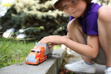 Photo of Little boy playing with toy car outdoors, selective focus