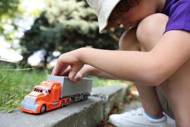 Photo of Little boy playing with toy car outdoors, closeup