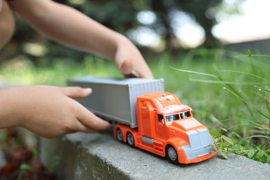 Photo of Little boy playing with toy car outdoors, closeup
