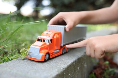 Photo of Little boy playing with toy car outdoors, closeup