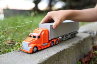 Photo of Little boy playing with toy car outdoors, closeup