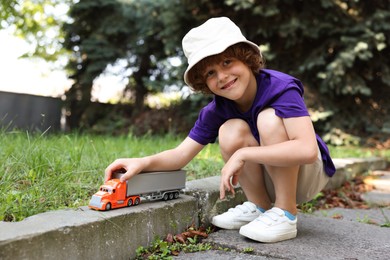 Photo of Little boy playing with toy car outdoors