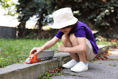 Photo of Little boy playing with toy car outdoors