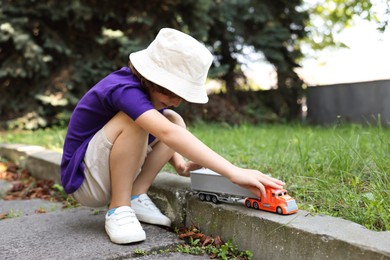 Photo of Little boy playing with toy car outdoors
