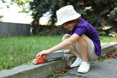 Photo of Little boy playing with toy car outdoors